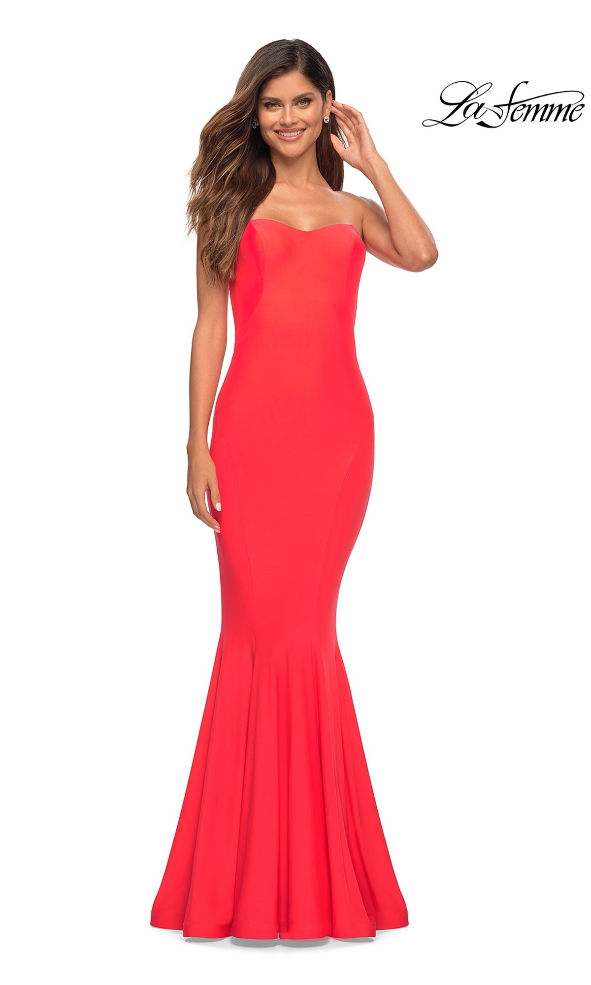 A woman stands and smiles against a white background, wearing the La Femme Hot Coral Simple Strapless Prom Dress. The La Femme logo appears in the top right corner.